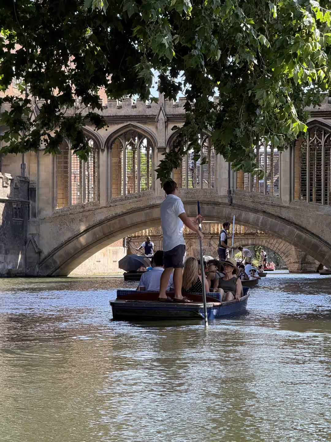A chauffeur poling a punt under a bridge on the River Cam, Cambridge